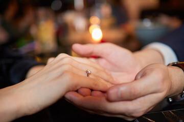 Young man putting ring on finger of his fiancee after marriage proposal, closeup.