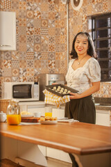 Asian young woman putting frozen cheese breads on the serving dish.