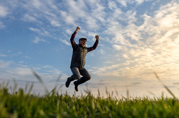 Joyful senior man jumping in field in spring