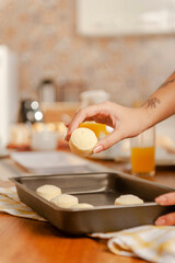 Young woman putting frozen chesse breads on the serving dish.