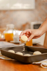 Young woman putting frozen chesse breads on the serving dish.