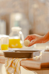 Young woman putting frozen chesse breads on the serving dish.
