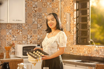 Asian young woman putting frozen cheese breads on the serving dish.