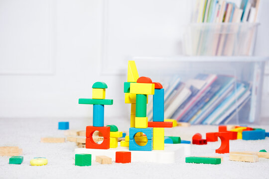 Toy wooden blocks form towers over boxes of books and toys