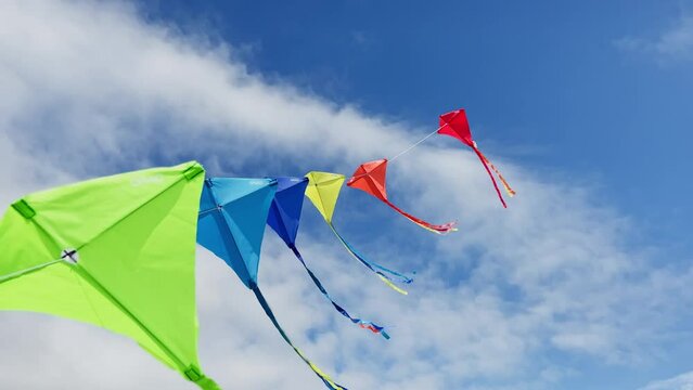 Group of colorful kites fly on the string over blue sky