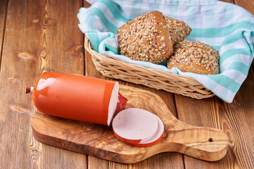 Boiled ham sausage sliced on a wooden kitchen board.