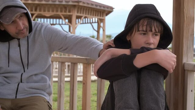 Father supporting girl on park bench. A pensive father try to support her young daughter on the bench in the day light.