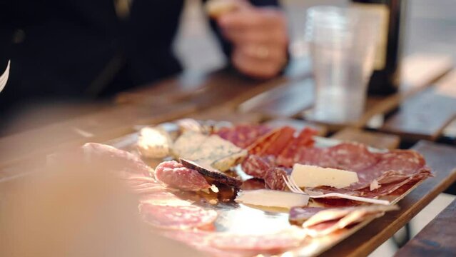 Traditional Italian aperitif in local restaurant of traditional cuisine, people tasting slices of high quality prosciutto di parma, salami, parmigiano cheese and typical gorgonzola, rustic snacks and