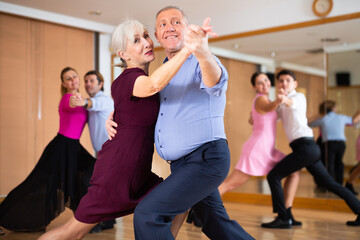 active elderly people attend dance lessons for amateurs and learn to dance tango in their free time