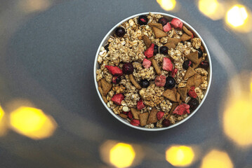 A bowl of muesli on a gray monochrome background, healthy food, healthy breakfast. With the glare...