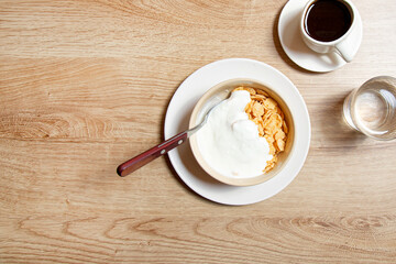 Obraz na płótnie Canvas Corn flakes with yogurt. Served with americano. Breakfast.