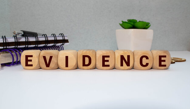 On a light background, wooden blocks with the text EVIDENCE. Close-up top view.