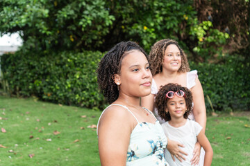Portrait of a teenage girl standing in the park with her family in the background.