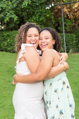 Fototapeta premium Hispanic mother and teenage daughter hug and smile at the camera