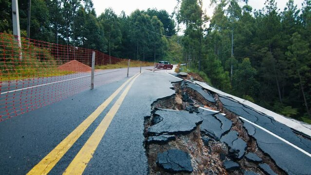 Damaged asphalt road in the mountains. Mudflow aftermath, cracked paved road