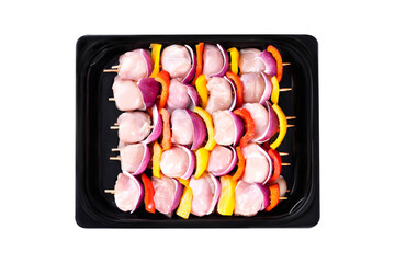 Skewers with pieces of raw meat, red, yellow and green pepper.Raw chicken skewers of fillet with vegetables, plums, peppers, onions, in a tray on a white background. Close-up.Top view.