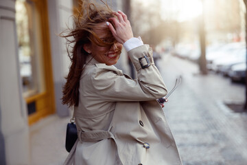 Fashionable smiling woman crossing the city street and looking at camera. High quality photo