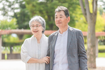 公園を話しながら歩く日本人の高齢者夫婦（シニア・男女）
