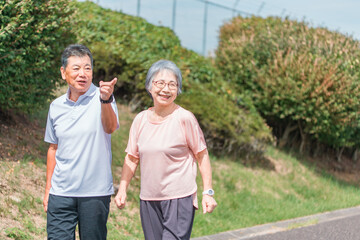 公園でウォーキング・有酸素運動する高齢者夫婦（シニア・男女）
