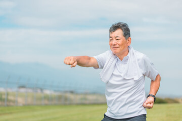 公園で太極拳・体操・カンフーなどの運動・リハビリをする高齢者男性
