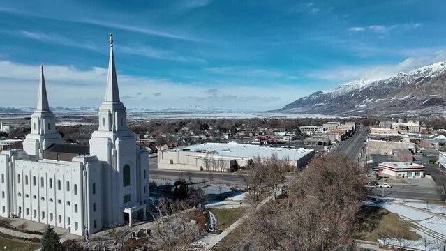 Aerial Brigham City Utah LDS Temple slide. The Church of Jesus Christ of Latter-day Saints, LDS or Mormon Church. Spiritual sacred church. Urban neighborhood in mountain valley. Winter snow.