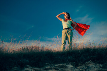 Superhero Woman Wearing a Red Cape Locking Far Away. Confident vigilante girl looking into the...