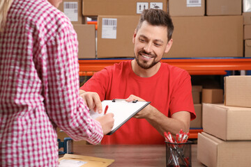 Woman signing papers for delivered parcel at post office