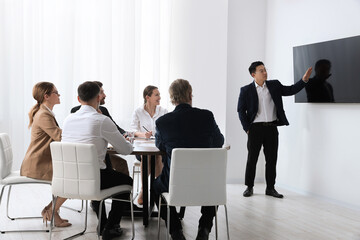 Business conference. Group of people listening to speaker report near tv screen in meeting room