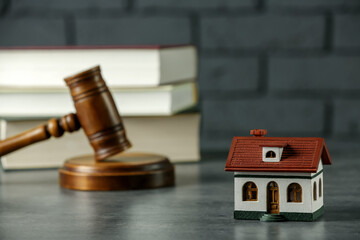 Construction and land law concepts. Judge gavel, house model with books on grey table