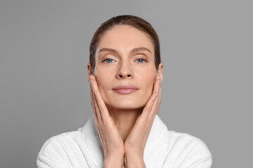 Woman massaging her face on grey background