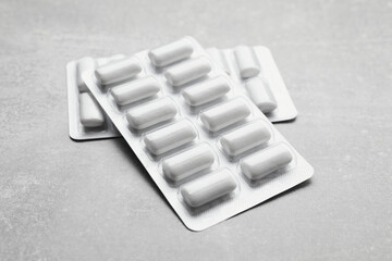 Blisters with chewing gums on light grey table, closeup
