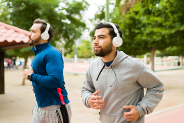 Attractive men running or jogging listening to music - obrazy, fototapety, plakaty