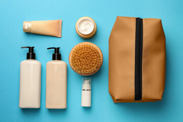 Preparation for spa. Compact toiletry bag and different cosmetic products on light blue background,...