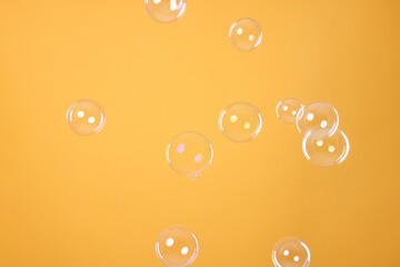 Many beautiful soap bubbles on orange background