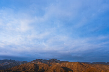 早朝の南アルプスに朝日があたり、青い空が広がっている