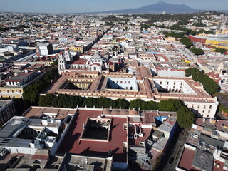 aerial photo view of the downtown of a hispanic city puebla, mexico, historical center with trees in the streets and colorful buildings, volcanos in the background