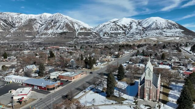 Aerial Brigham City Utah LDS Temple toward mountain. The Church of Jesus Christ of Latter-day Saints, LDS or Mormon Church. Spiritual sacred church. Urban neighborhood in mountain valley. Winter snow.