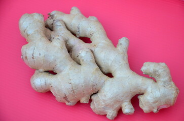 Ginger root lies on a crimson surface.