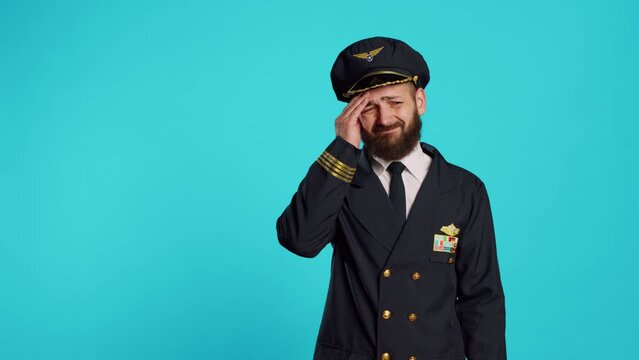 Sick airplane pilot suffering from headache, being worried about painful migraine and feeling ill. Professional airline captain being unhappy and in pain, feeling pressure rubbing temples.