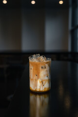 Iced coffee latte on a table with cream being poured into it, showcasing its texture.