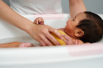 Fototapeta na wymiar mother give a bath newborn baby in bathtub