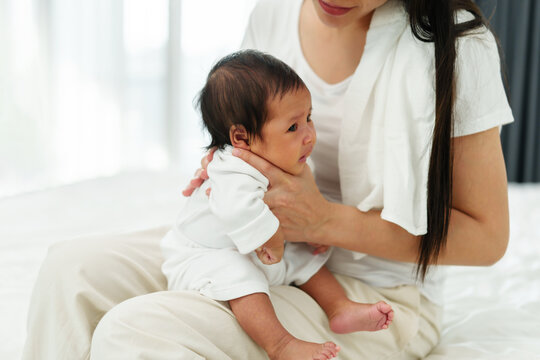 Mother Holding Newborn Baby Burping In Bedroom After Feeding Milk