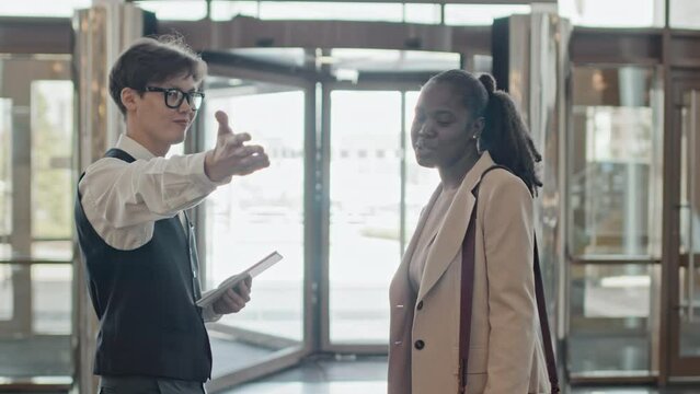 Young African American woman asking Asian hotel worker for direction to her room