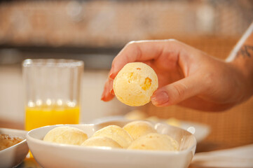 Female hand picking up a cheese bread. (Pao de queijo)