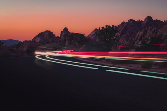 Light trails from cars driving through Joshua Tree National Park at sunset.