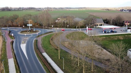Roundabout of asphalt in a small village of Dutch countryside. Flow of transport and car transport. Aerial view of road traffic point.