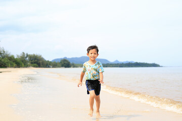 Fototapeta na wymiar Asian little boy having fun running on tropical sand beach.