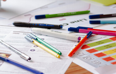 pen and markers on printed charts on a table 