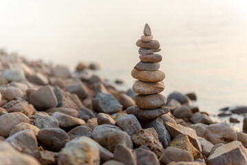 The stones of the pyramid balance on the rock. The background of the evening sea is blurred. Selective focus.