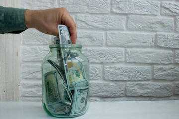 Mens hand taking out paper dollar banknote from glass jar,financial conceptual image,economic crisis,saving money for health,pension deposit,keeping heap of cash at home bank